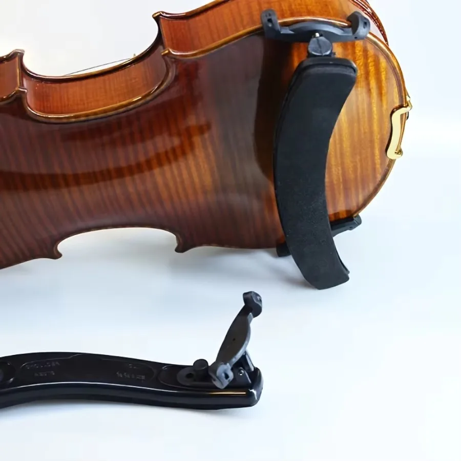 Side view of the black foam-cushioned Cadenza shoulder rest mounted on an amber violin, with a second unit lying flat below showing the underside and foldable feet